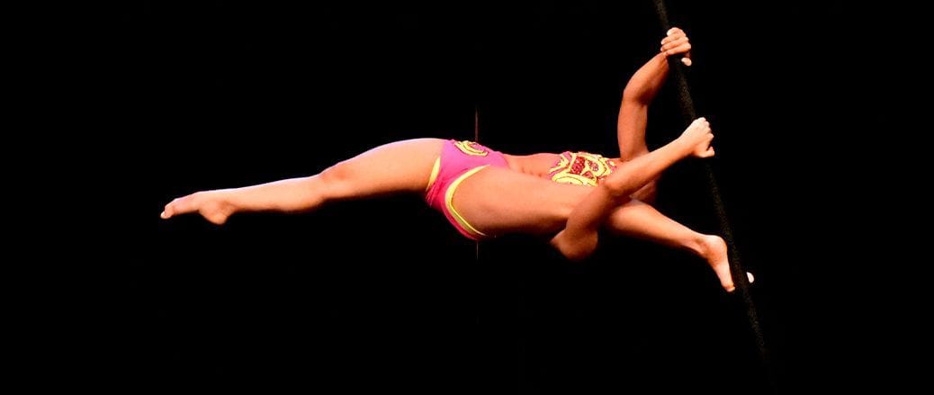 Mulher realizando movimento no pole dance com suporte para teto