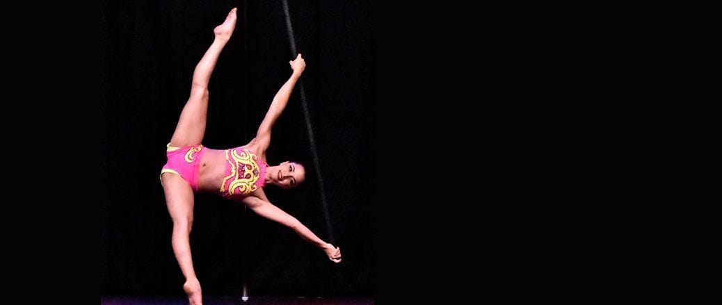 Mulher realizando tipo de movimento no pole dance com suporte para teto